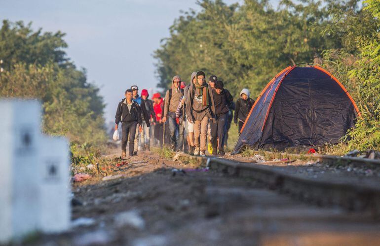 Migrantes procedentes de Serbia caminan por la vía del tren junto a la población fronteriza de Roszke.