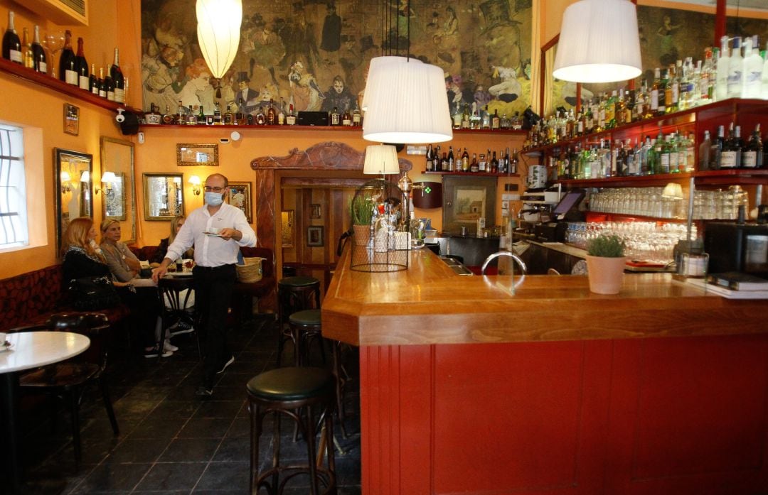 Un camarero sirve una mesa en un bar.