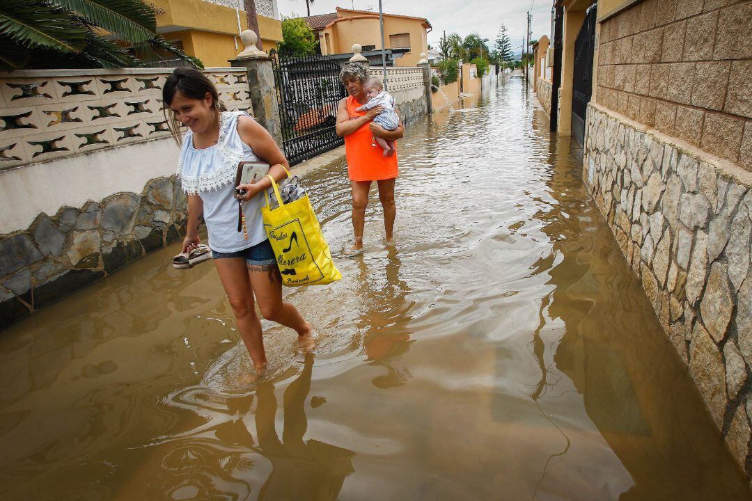 Dos mujeres caminan por una calle inundada en de una de las urbanizaciones de la playa de Peñíscola afectadas por la intensa tormenta que ha caído esta mañana en el litoral norte de la provincia de Castellón que ha dejado algunas carreteras secundarias cortadas y ha provocado el rescate de seis vehículos en Benicarló, además de un pequeño accidente en Peñíscola y problemas por erosión en la playa del Clot de Vinaròs.