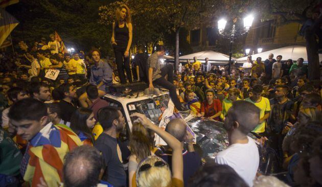 Gente subida encima de un coche destrozado de la Guardia Civil