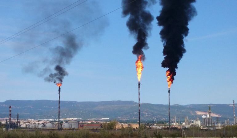 Pla obert amb les dos torxes de Repsol i Dow a l&#039;esquerra amb les denses columnes de fum negre visibles a molts quilòmetres. 