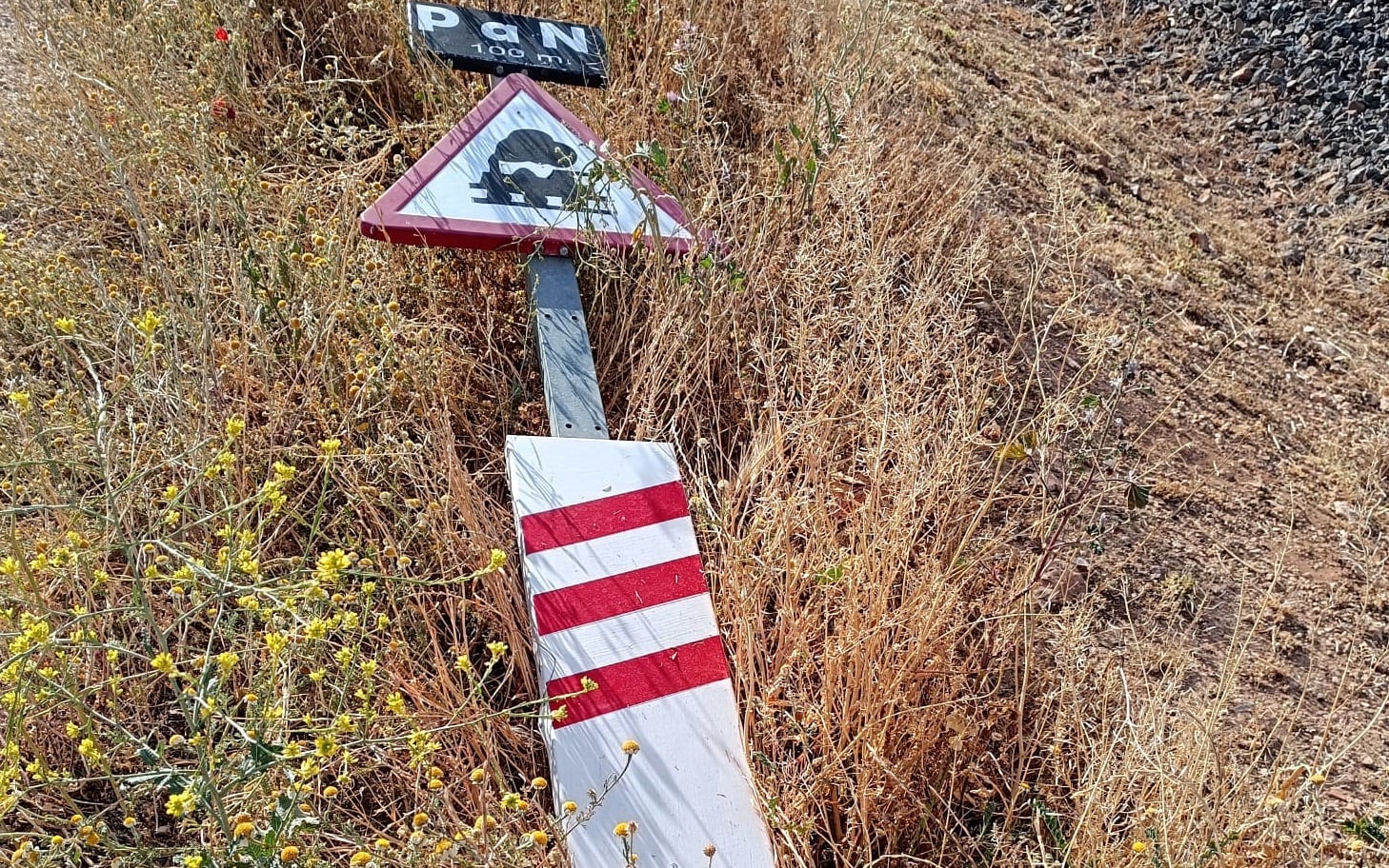 Señal de &quot;paso a nivel&quot; tirada en el suelo