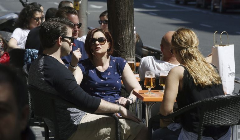 Varias personas disfrutan hoy al mediodía del sol en una terraza de un bar en Madrid.