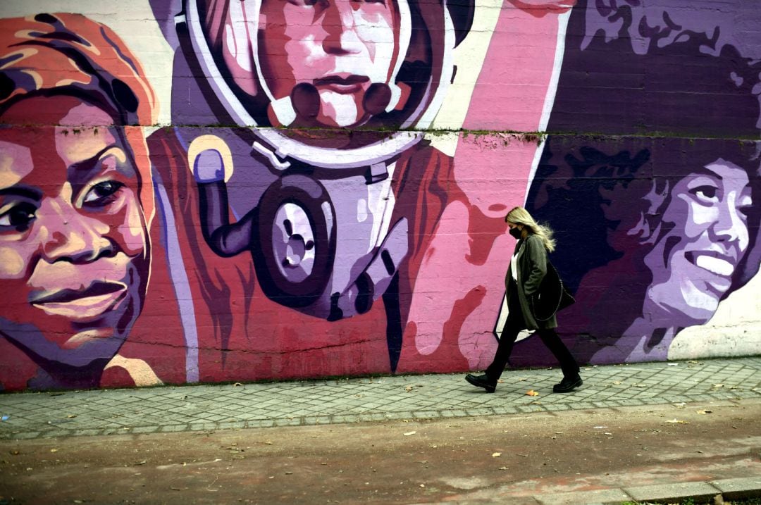 Una mujer pasa por el mural feminista en el polideportivo municipal de la Concepción en el distrito de Ciudad Lineal, en Madrid.