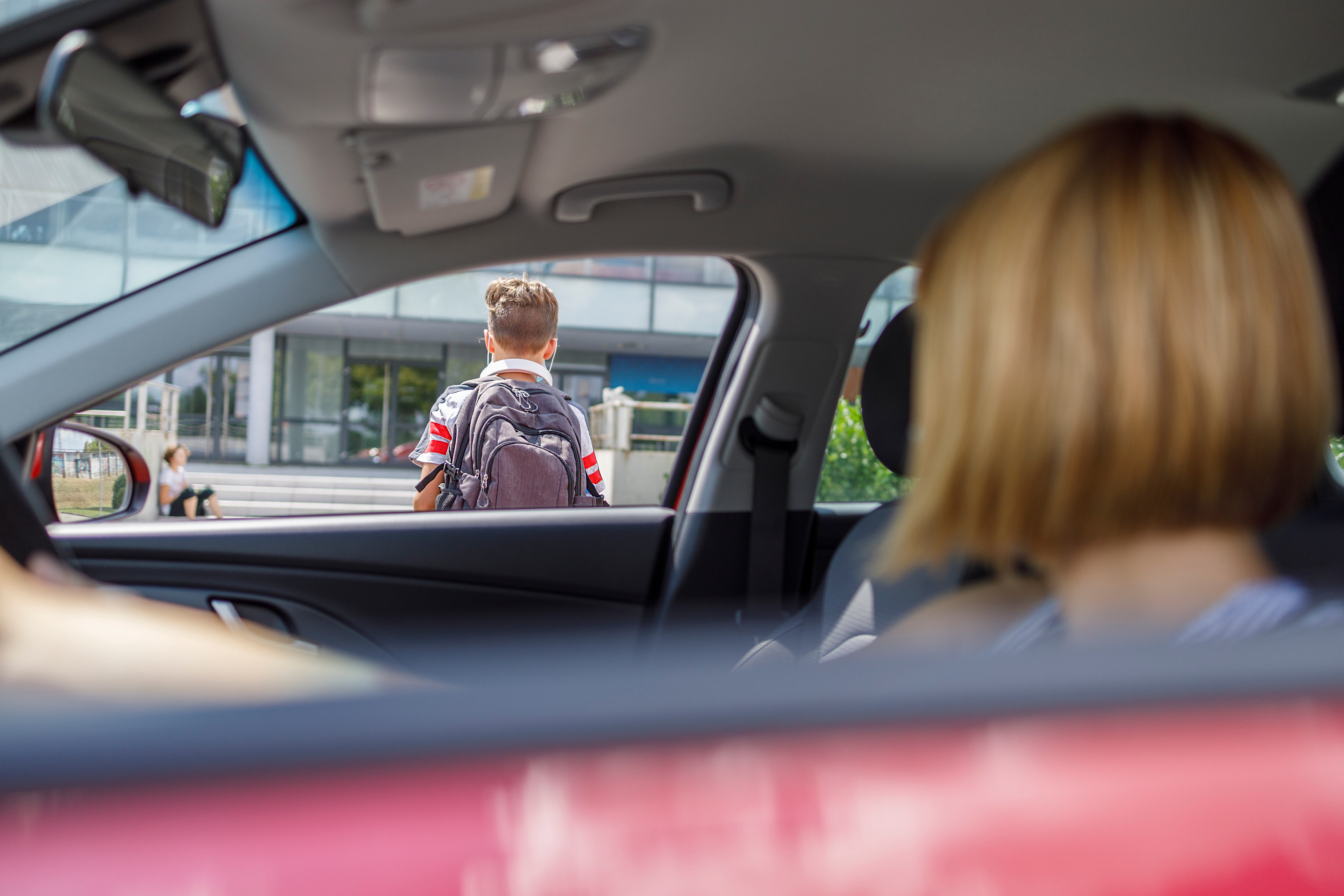 Una mujer observa a su hijo entrando en el colegio