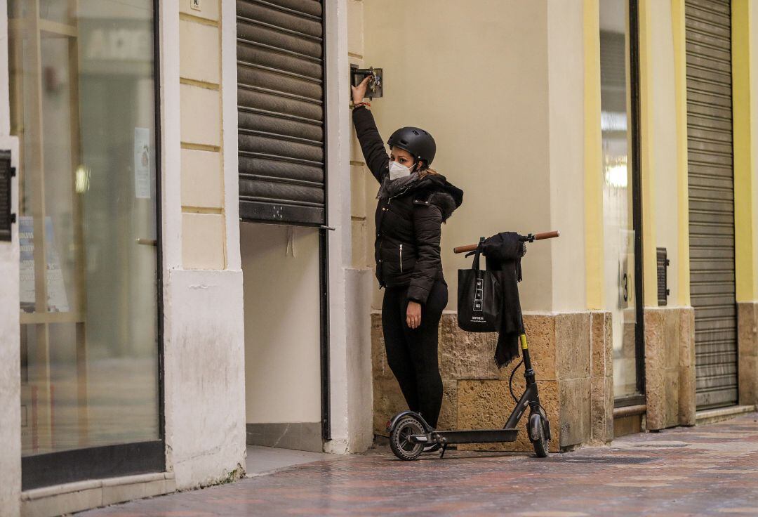 La trabajadora de un comercio cierra su establecimiento el primer día del cierre total de la hostelería y de tiendas a las 18.00h en València