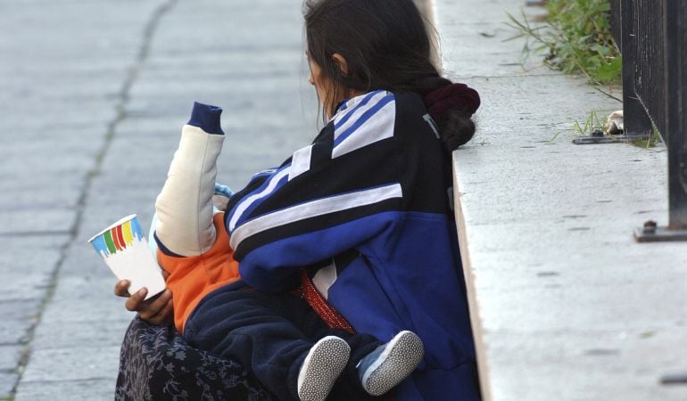 Una mujer sin techo pide con su hijo en la calle en Roma.