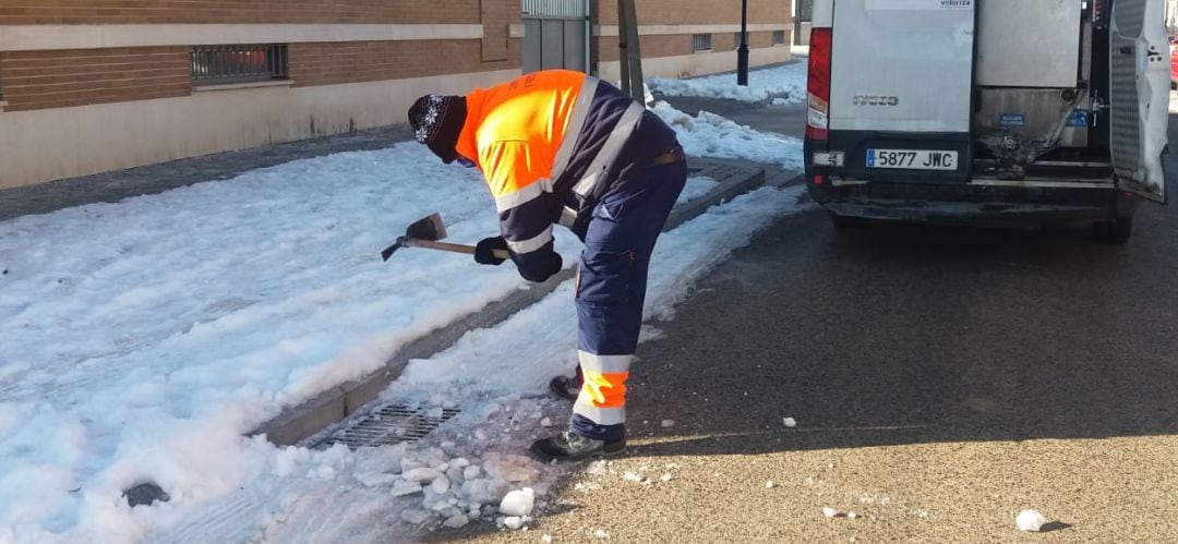 Un trabajador del servicio de limpieza viaria quita el hielo de un imbornal para que no se atasque antes del deshielo