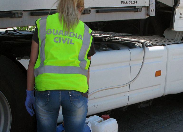 Una agente de la Guardia Civil comprueba unos bidones con gasoil junto a un camión