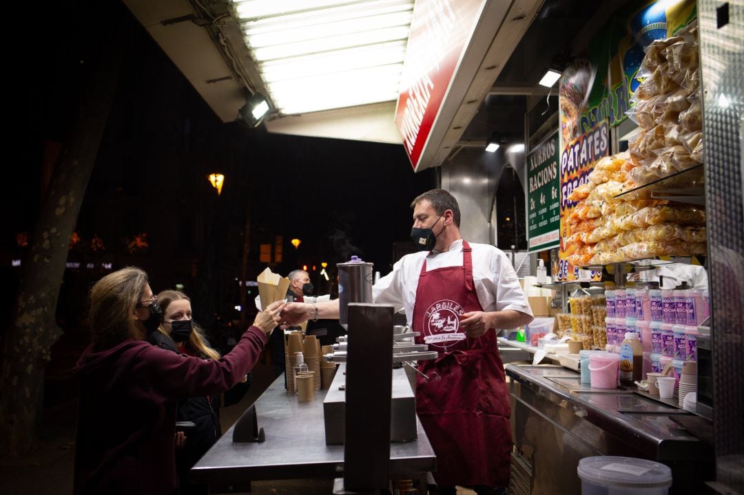 Dos chicas en un tenderete de comida en la Feria de Reyes de la Gran Vía, a 29 de diciembre de 2021, en Barcelona.