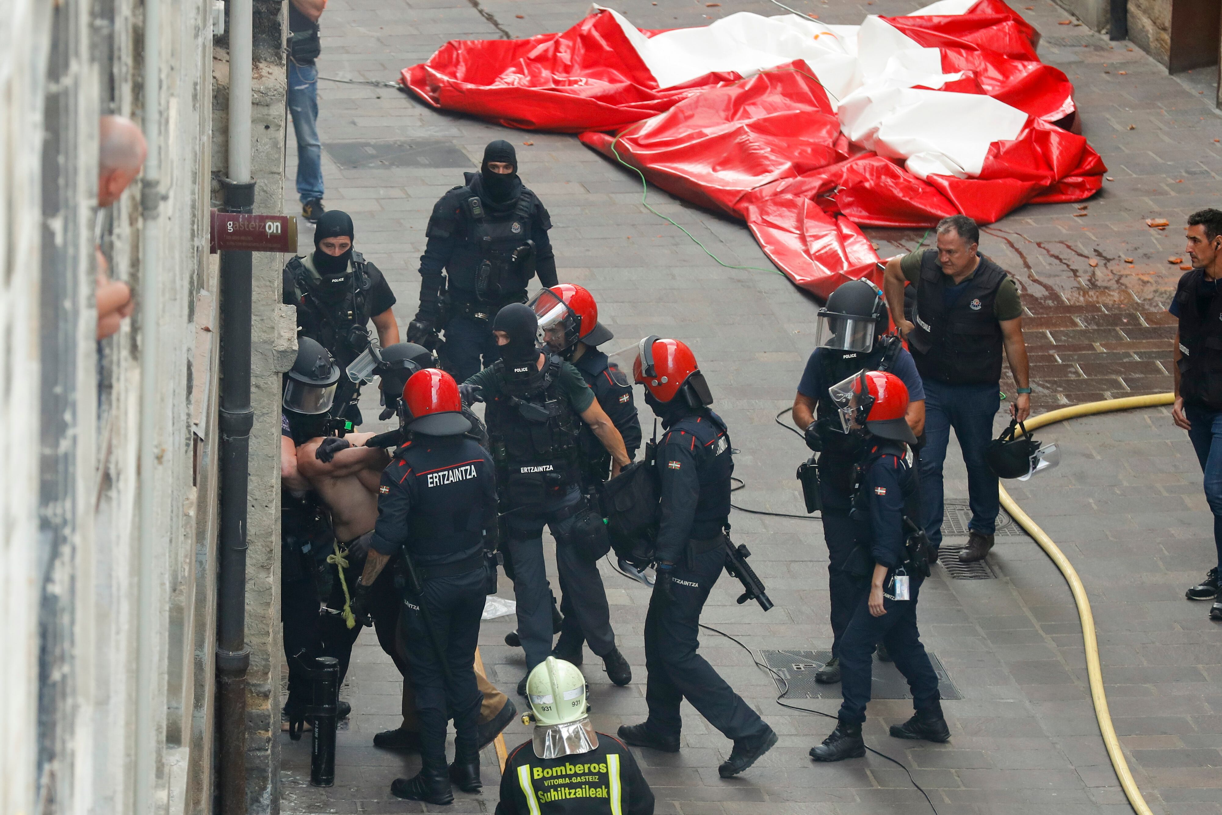 El hombre que se ha atrincherado en su piso en el Casco Viejo de Vitoria (i), es arrestado por agentes de la Ertzaintza, este domingo en Vitoria.