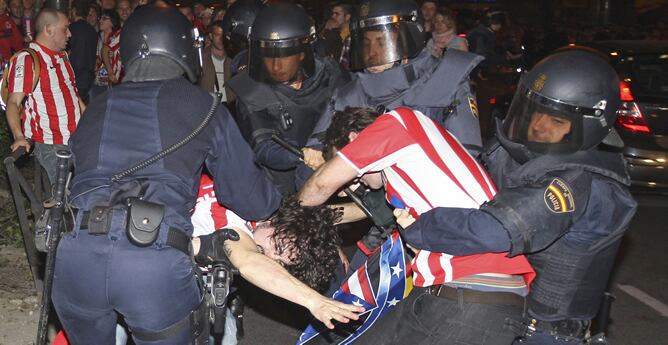 Miembros de la policia nacional intentan reducir a varios aficionados del Atlético de Madrid que han protagonizado altercados durante las celebraciones en la plaza de Neptuno