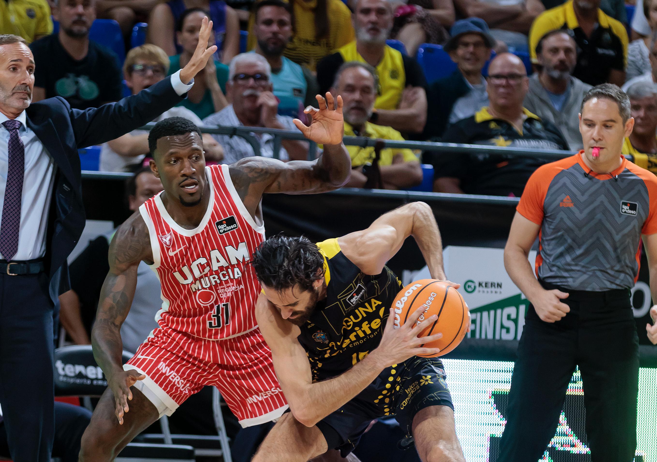 Dylan Ennis, jugador de UCAM Murcia, defiende ante La Laguna Tenerife, bajo la mirada de Sito Alonso.