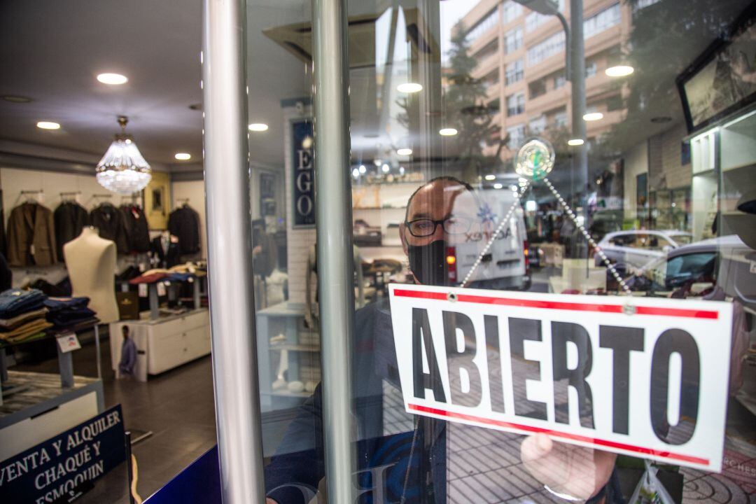 Archivo - Un comercio muestra en su puerta un cartel donde se lee &quot;abierto&quot;