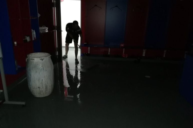 Un trabajador del Eibar achica agua de uno de los vestuarios de Ipurua