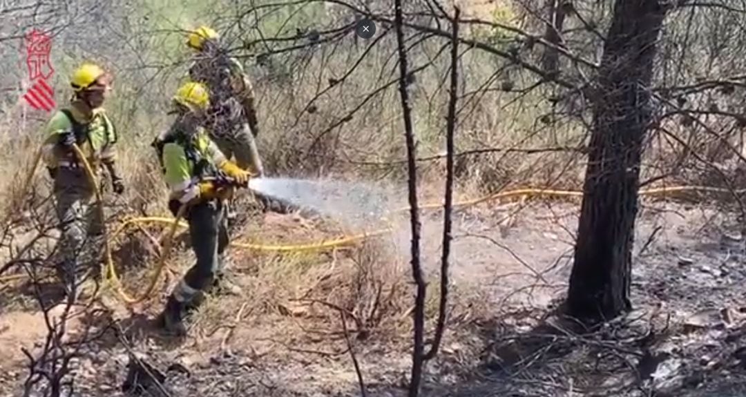 Bomberos refrescando la zona quemada del perímetro por precaución.