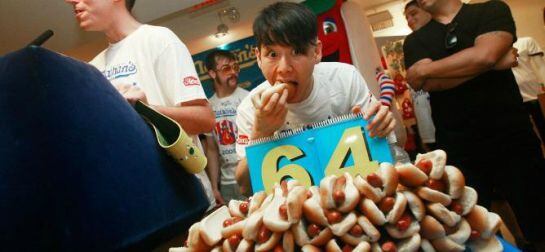 Un joven comiendo perritos calientes