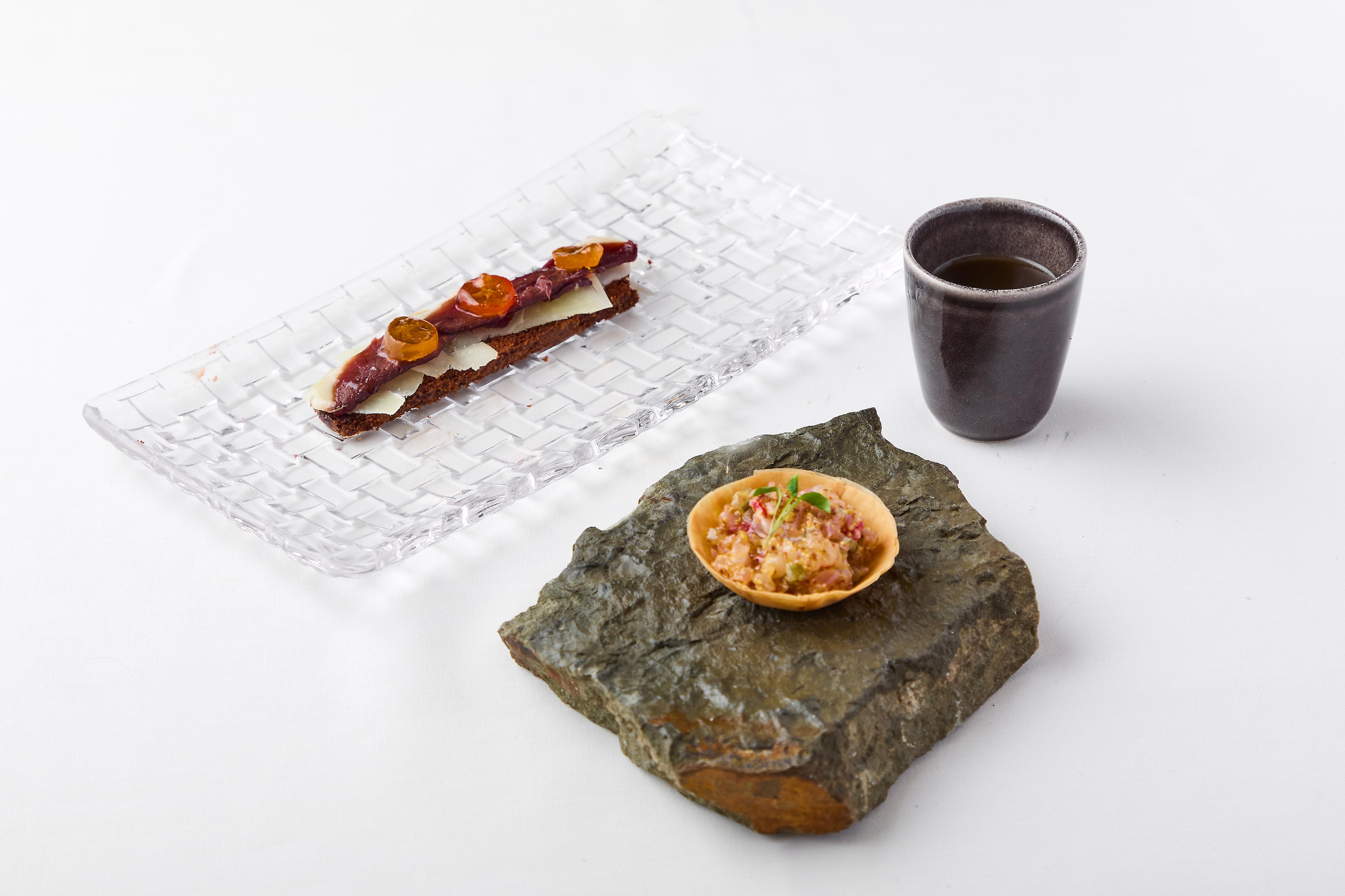 Raíces y Origen:Consomé Tradicional - Tartaleta de marisco. Magret de pato y Kunkut crujiente de ajo negro y lascas de queso.