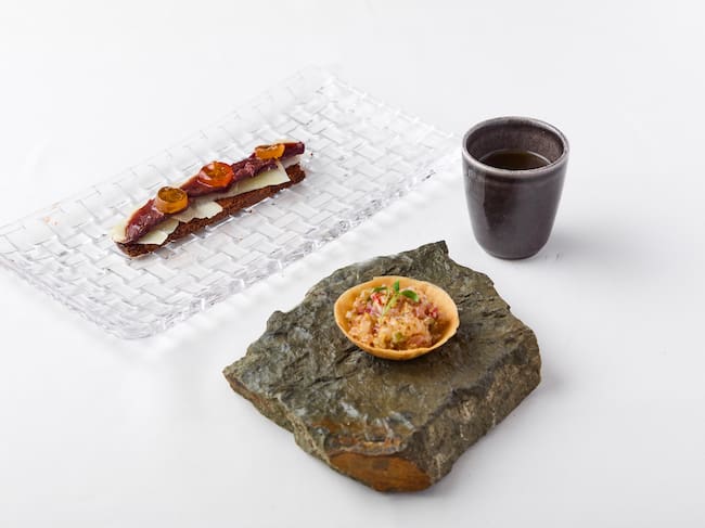 Raíces y Origen:Consomé Tradicional - Tartaleta de marisco. Magret de pato y Kunkut crujiente de ajo negro y lascas de queso.