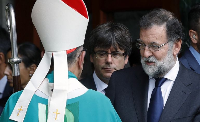 El presidente del Gobierno, Mariano Rajoy, junto al presidente de la Generalitat de Cataluña, Carles Puigdemont (i), se despiden del el arzobispo metropolitano de Barcelona, cardenal Juan José Omella, a su salida de la basílica de la Sagrada Familia donde