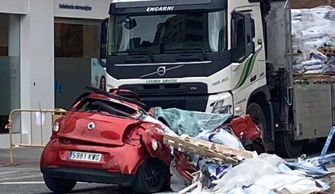 Estado del coche tras caerle la carga de un camión grúa en Granada.