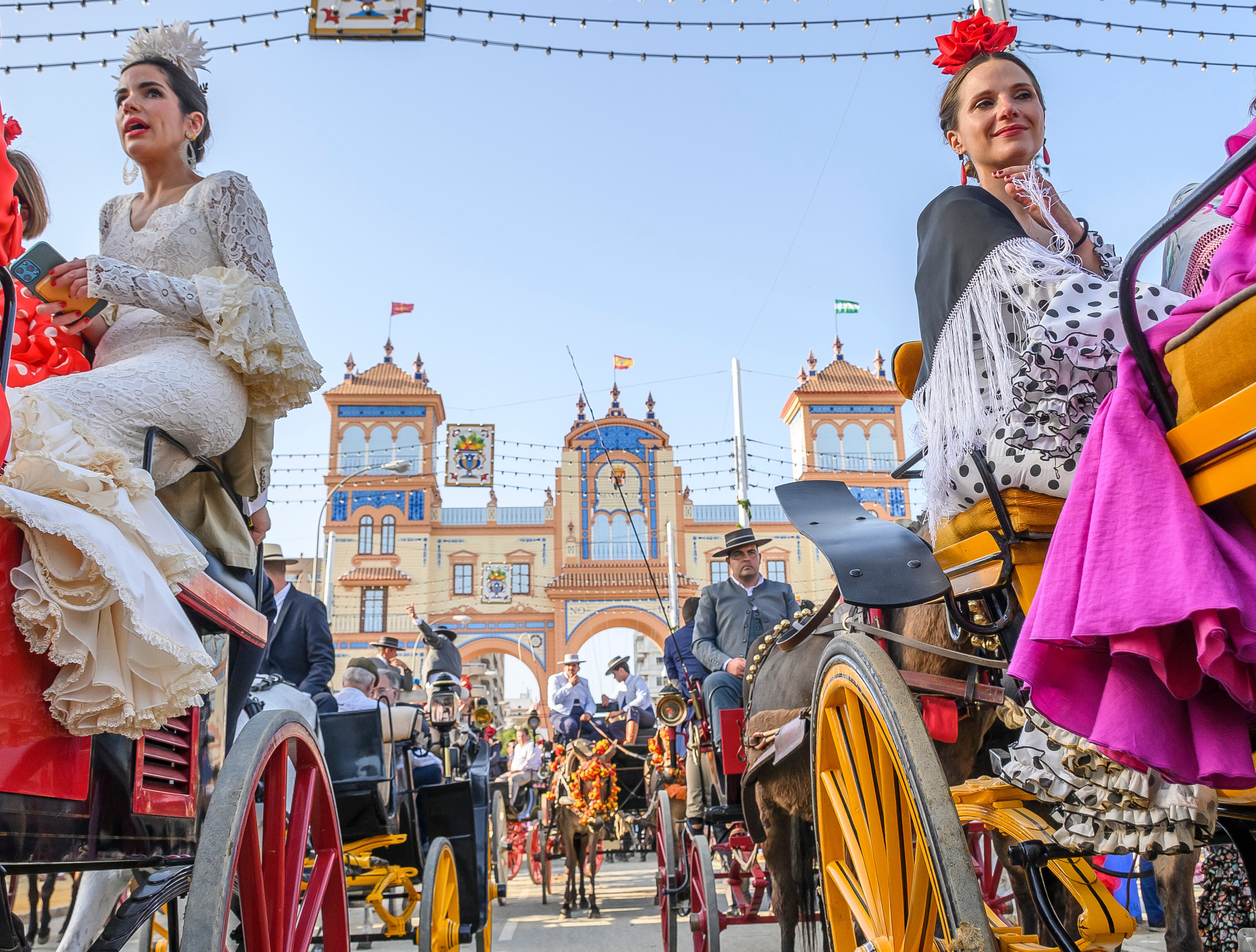 SEVILLA, 01/05/2022.- Un momento del Paseo de Caballos con la Portada al fondo en el Real de la Feria de Abril de Sevilla. Después de estar dos años suspendida a causa de la pandemia de coronavirus, la Feria de Abril de Sevilla (sur español) vuelve a celebrarse desde este domingo con el bullicio y la alegría característicos y las ganas de diversión con familiares y amigos durante unos días primaverales. EFE/ Raúl Caro.
