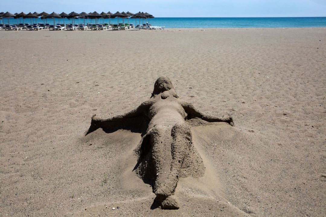 Una figura realizada con arena permanece en la playa de Playamar, totalmente vacía, este domingo en Torremolinos, Málaga, durante el Estado de Alarma decretado para evitar la propagación del coronavirus 