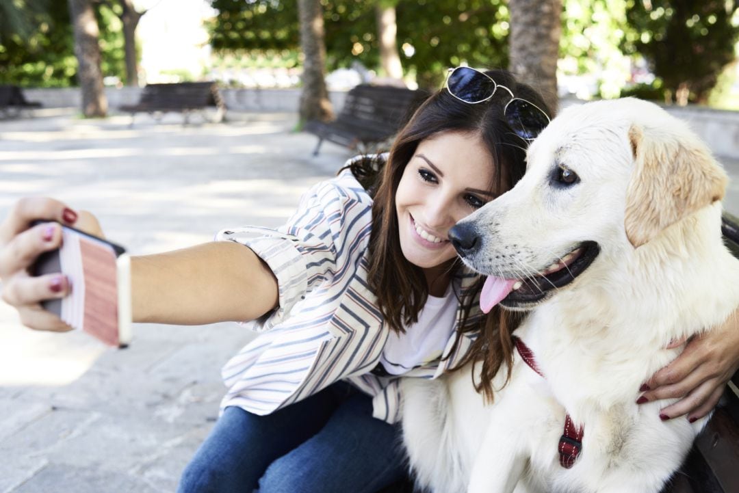 Una mujer se hace un selfi con su perro en la calle.