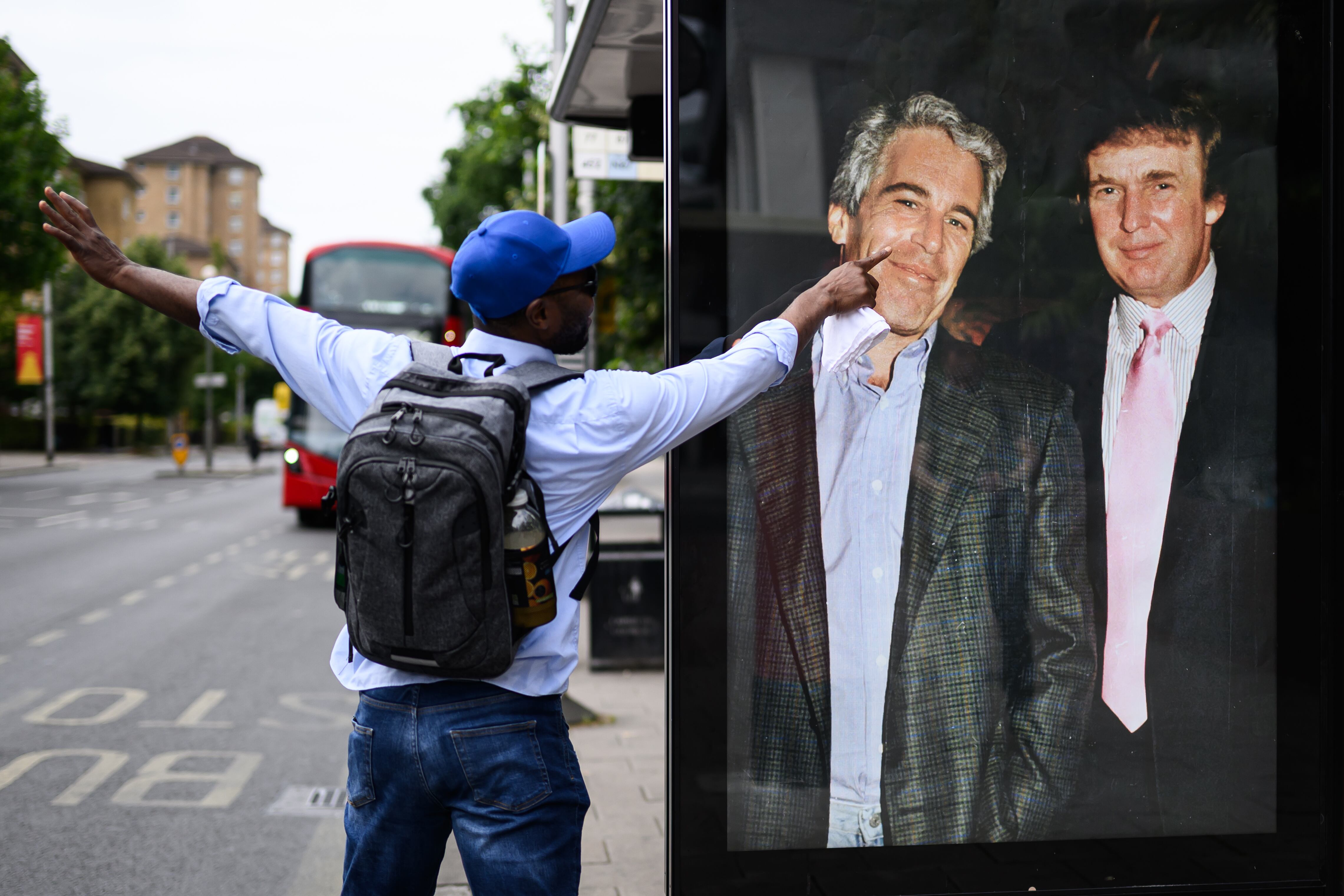 Un hombre señala una fotografía del presidente de Estados Unidos, Donald Trump, junto a Jeffrey Epstein, colocada de forma no autorizada en señal de protesta en una parada de autobuses de Londres.