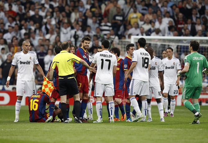 El centrocampista del F. C. Barcelona Sergio Busquets (2i), en el suelo rodeado de jugadores de su equipo y del Real Madrid, durante el partido correspondiente a la ida de la semifinal de la Liga de Campeones, que ambos equipos disputan esta noche en el e