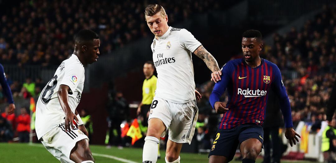 Vinicius y Kroos tratan de llevarse la pelota ante Nelson Semedo