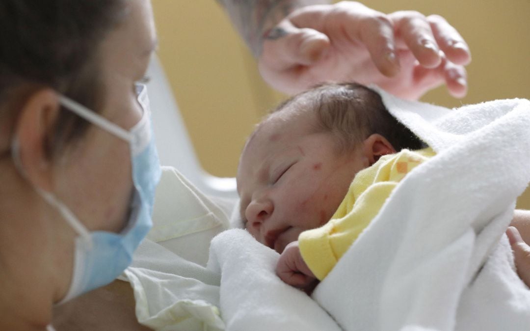 Una mujer con su hijo recién nacido entre sus brazos. 