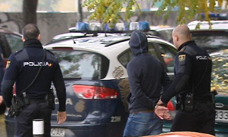 Imagen de televisión de efectivos de la Policía Nacional que conducen a uno de los 21 detenidos en la reyerta en Madrid Río producida entre radicales del Deportivo de La Coruña y del Atlético.