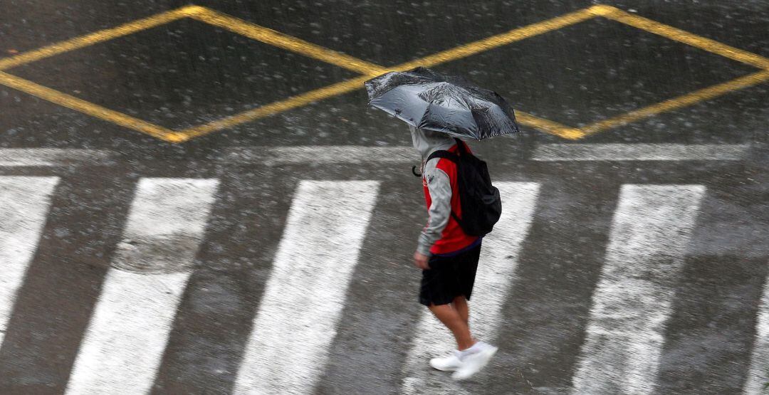 Una persona se protege de la lluvia con un paraguas durante la mañana de hoy en la que el cielo de la Comunidad Valenciana permanece cubierto, con precipitaciones fuertes o muy fuertes, sobre todo en Castellón y Valencia.