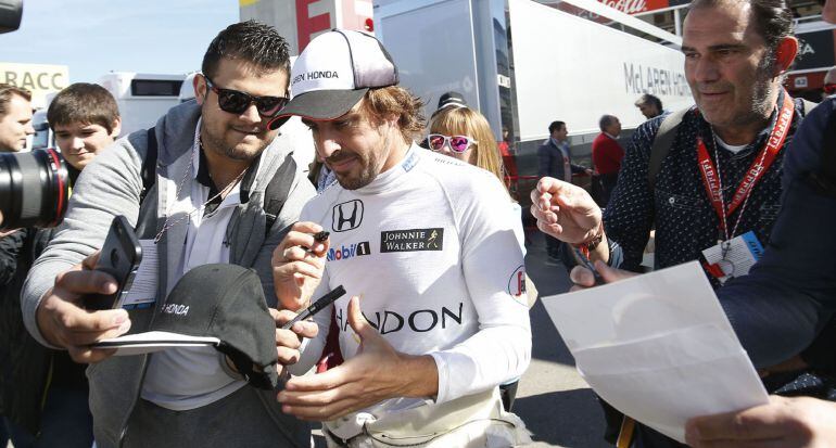 El piloto español Fernando Alonso firma autógrafos durante un descanso de los entrenamientos oficiales de Fórmula 1 de Montmeló.