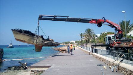 Momento en que se retira de la playa el velero incendiado