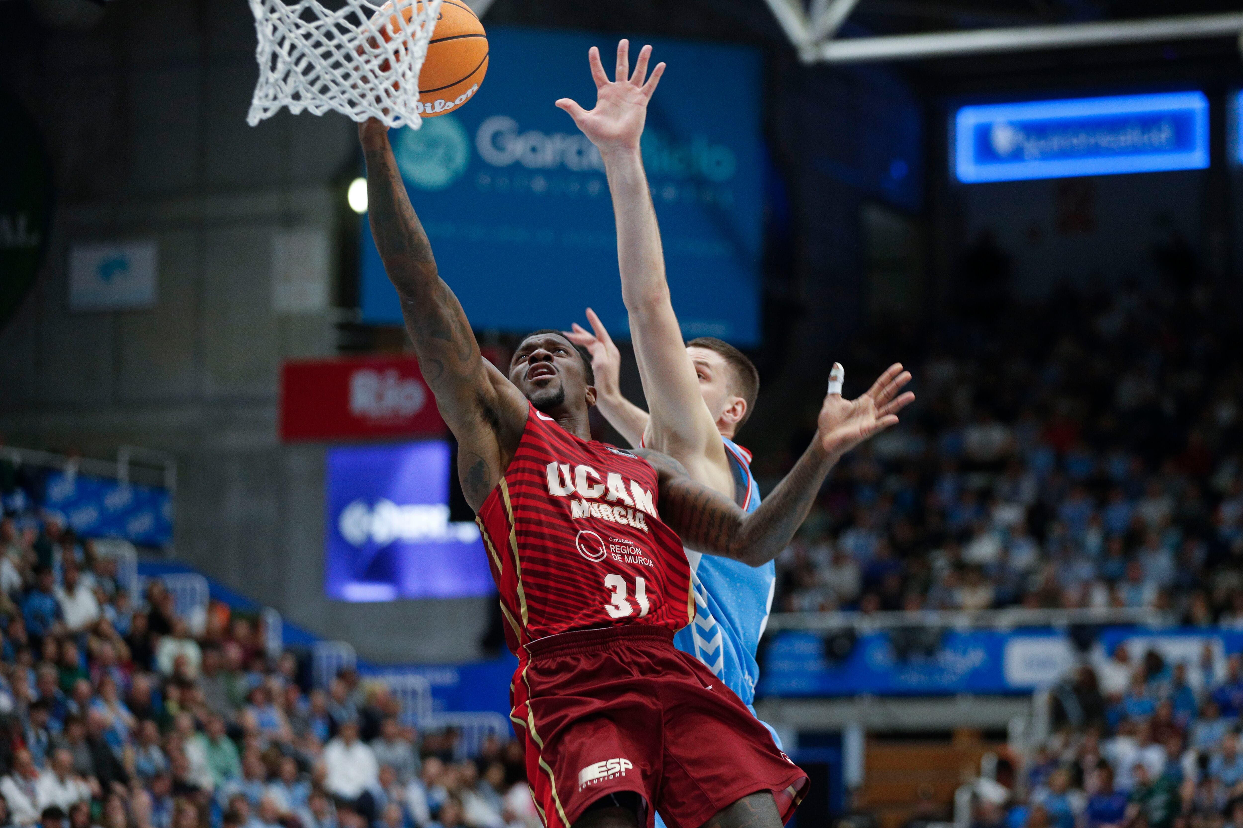 LUGO, 22/03/2025.- El escolta del UCAM Dyland Ennis (i) entra a canasta ante Dragan Apic, del Breogán, durante el partido de la Liga Endesa de baloncesto que Río Breogán y UCAM Murcia disputan este sábado en Lugo. EFE/Eliseo Trigo