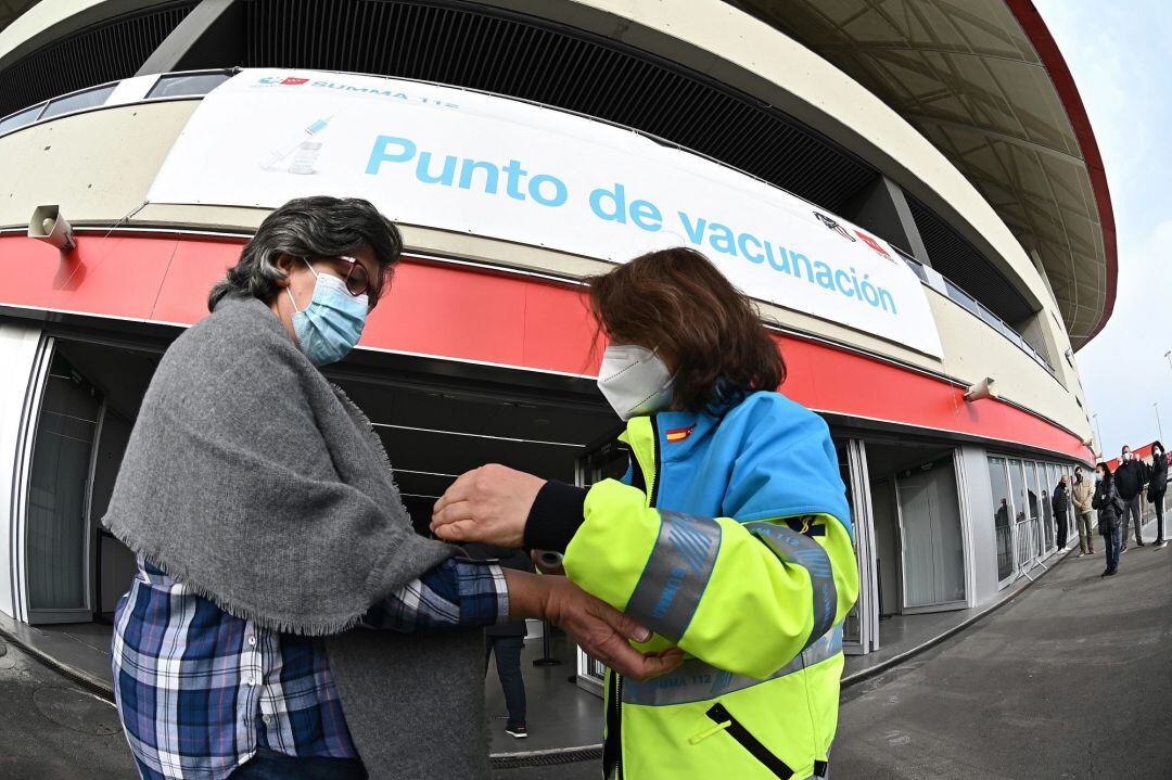 Una mujer toma la temperatura a los mayores que acuden al estadio Wanda Metropolitano en Madrid, que acoge este martes el inicio de la vacunación con Astrazeneca para la población general de 60 a 65 años.