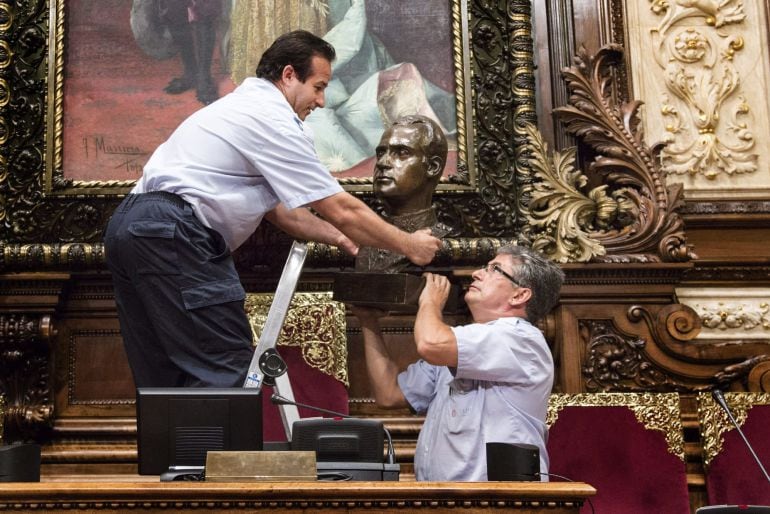 BARCELONA, 23/07/2015.- Dos operarios municipales retiran el busto del Rey Juan Carlos I que hay en el Salón de la Reina Regente, donde se celebran los plenos municipales del Ayuntamiento de Barcelona, después de que el equipo de gobierno municipal de la alcadesa Ada Colau haya anunciado su retirada con el argumento de que resuelve &quot;una situación anómala&quot;, dada porque Don Juan Carlos &quot;no es Jefe del Estado desde junio de 2014&quot; y además, hay un sobredimensionamiento de la simbología monárquica en el ayuntamiento