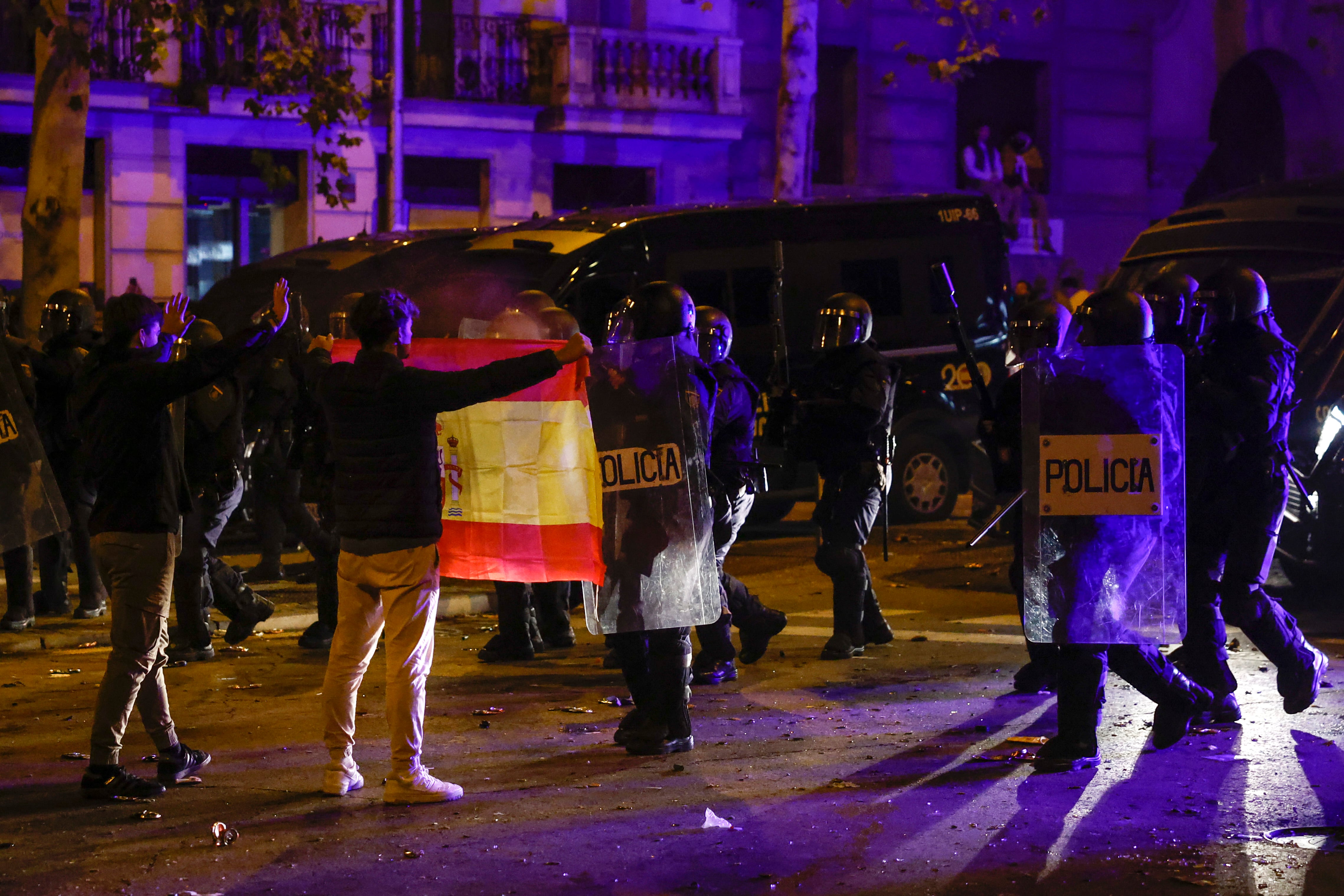 Una persona enseña una bandera de España a la policía durante una nueva manifestación convocada contra la amnistía, frente a la sede del PSOE en Ferraz, Madrid. EFE/ Sergio Perez