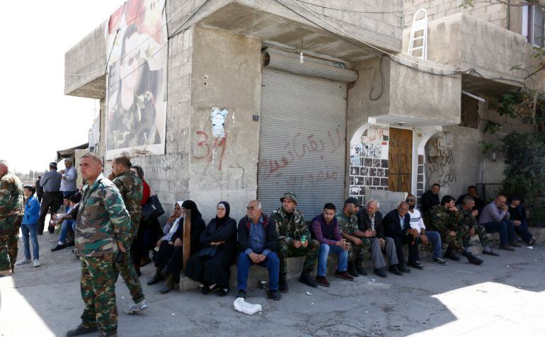 Soldados permanecen junto a familiares de personas supuestamente detenidas por combatientes del Ejército del Islam durante la evacuación de combatientes y familiares de dicho ejército desde Duma