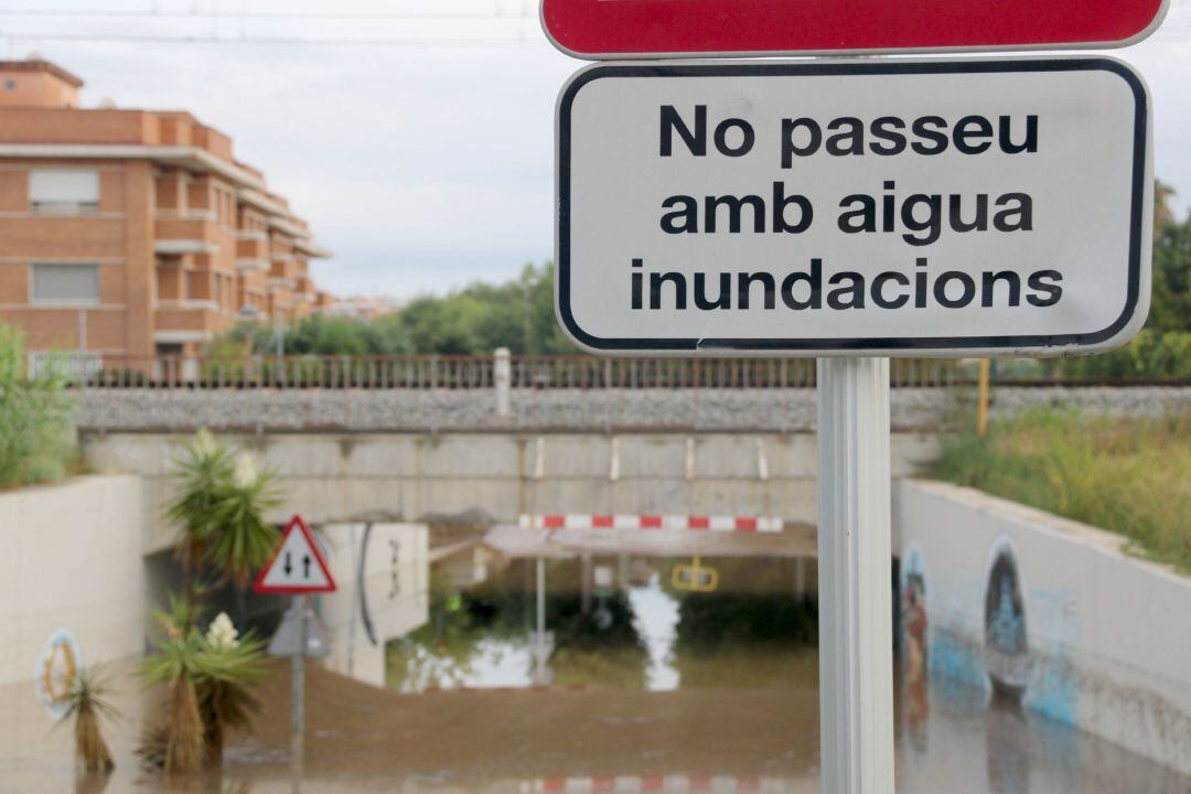 Senyal que restringeix el trànsit en un pas sota via a Cubelles en cas d'inundacions, amb el mateix pas inundat. Imatge del 12 d'agost del 2019