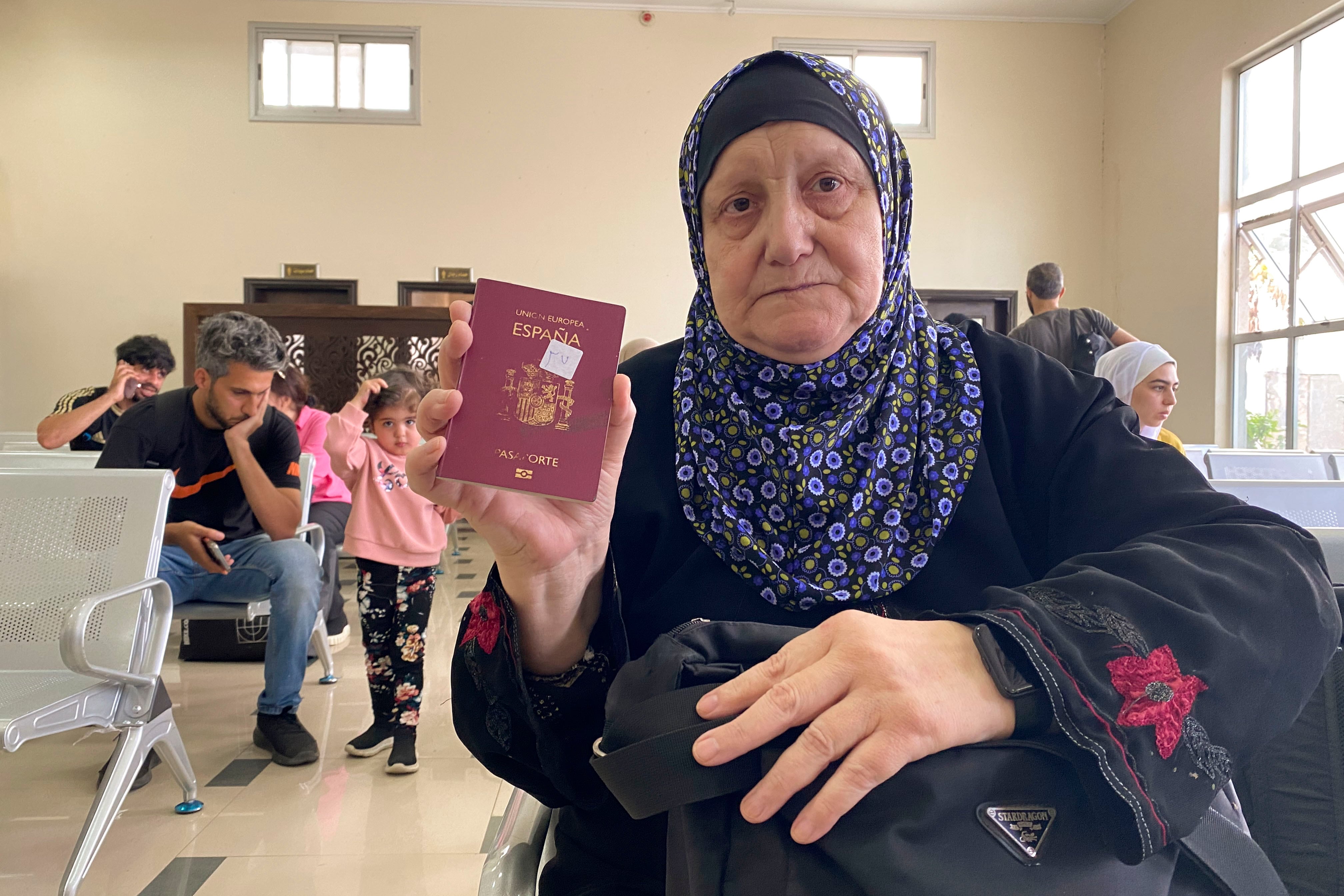 En la imagen, una mujer muestra su pasaporte español mientras espera a poder salir de Gaza.