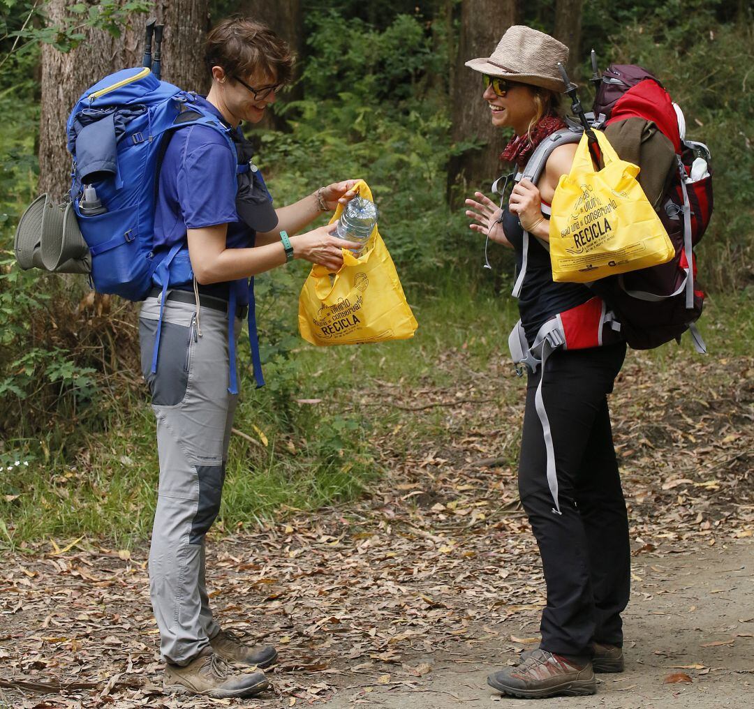 Dos peregrinas utilizan las bolsas de la campaña &quot;Camino del Reciclaje&quot; a su paso por el Camino de Santiago, para reciclar los residuos (envases y papel-cartón) que generan en cada etapa.