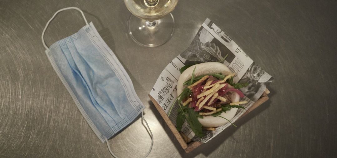 Archivo - Una copa de vino llena, junto a una mascarilla y una tapa.