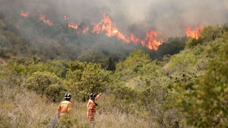  Dos bomberos observan las llamas cerca de la localidad de Sumacarcer (Valencia). La Unidad Militar de Emergencias (UME) ha desplegado 229 efectivos, con 64 vehículos, en labores de extinción del incendio forestal declarado ayer en el término de Bolbaite 