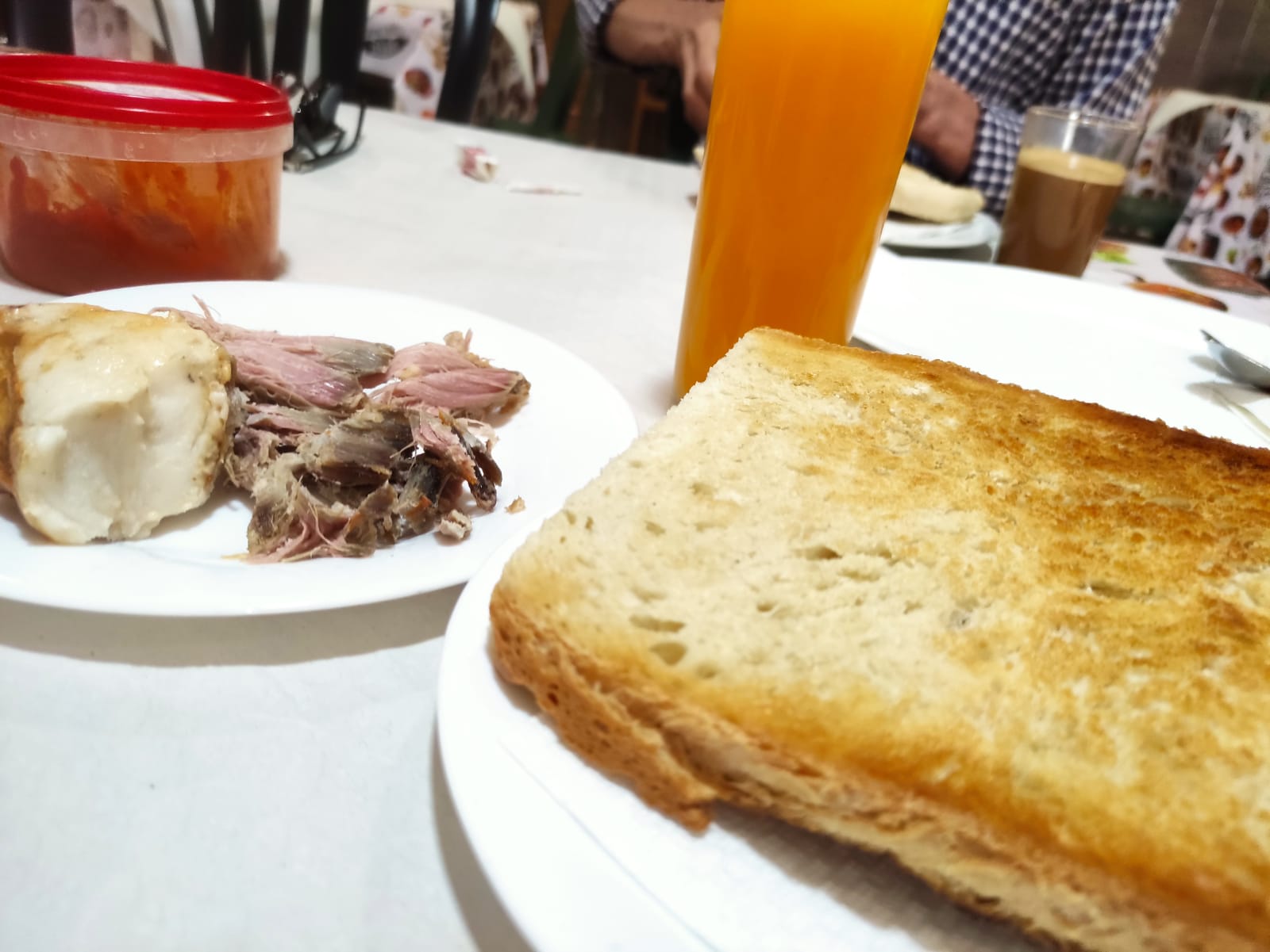 Rebanada de pan de telera con pringá y zumo de naranja en la Venta El Pollo