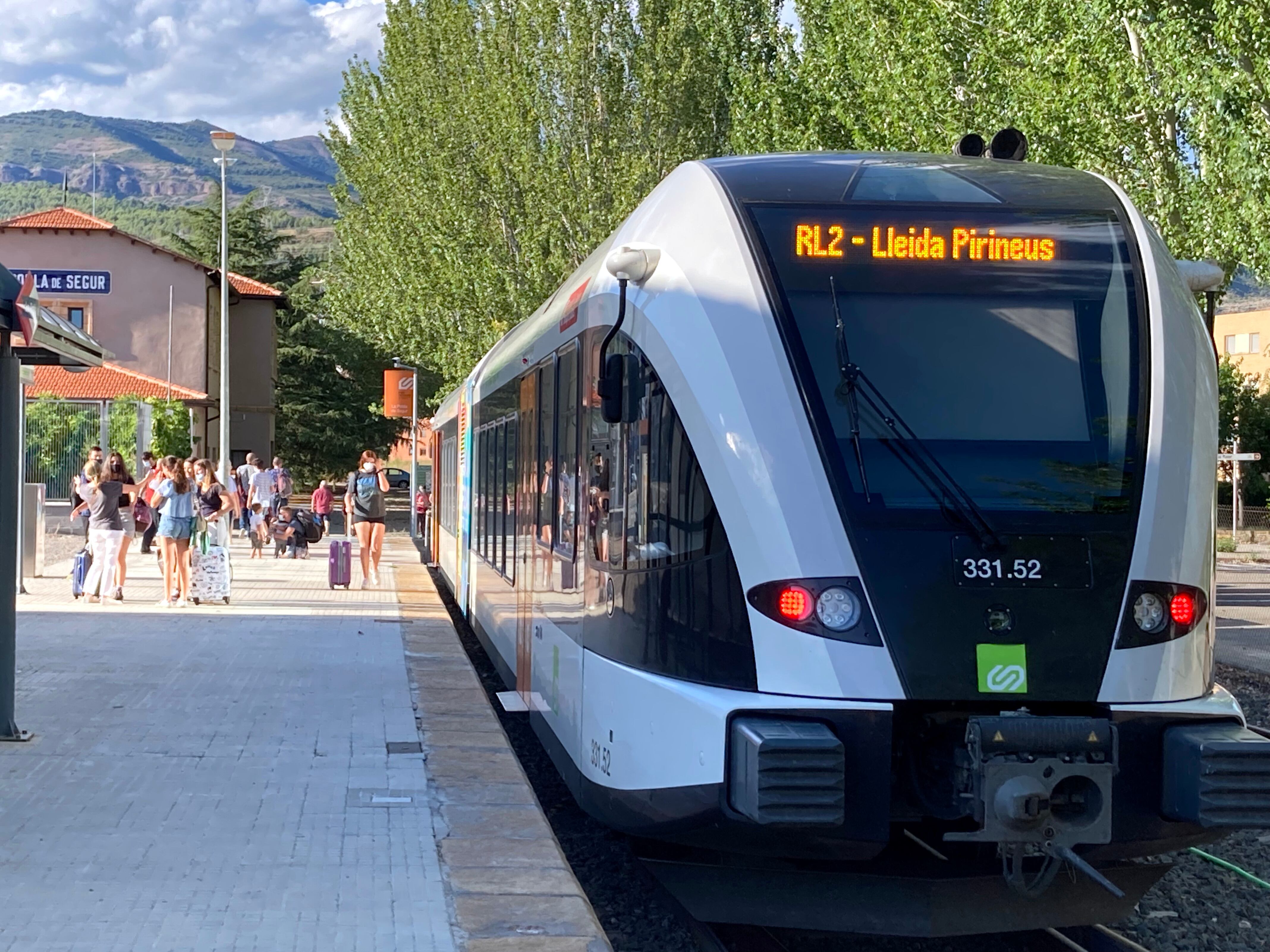 Pla obert on es pot veure el tren de la línia de la Pobla a l'arribada a l'estació de la Pobla de Segur amb alguns turistes acabats de baixar, l'agost de 2021. (Horitzontal)