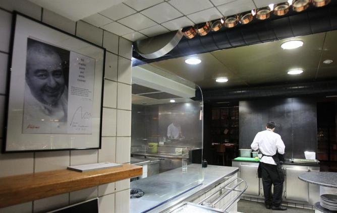 Vista de la cocina del restaurante Can Fabes de Sant Celoni, presidida por una gran fotografía del malogrado cocinero catalán Santi Santamaría.