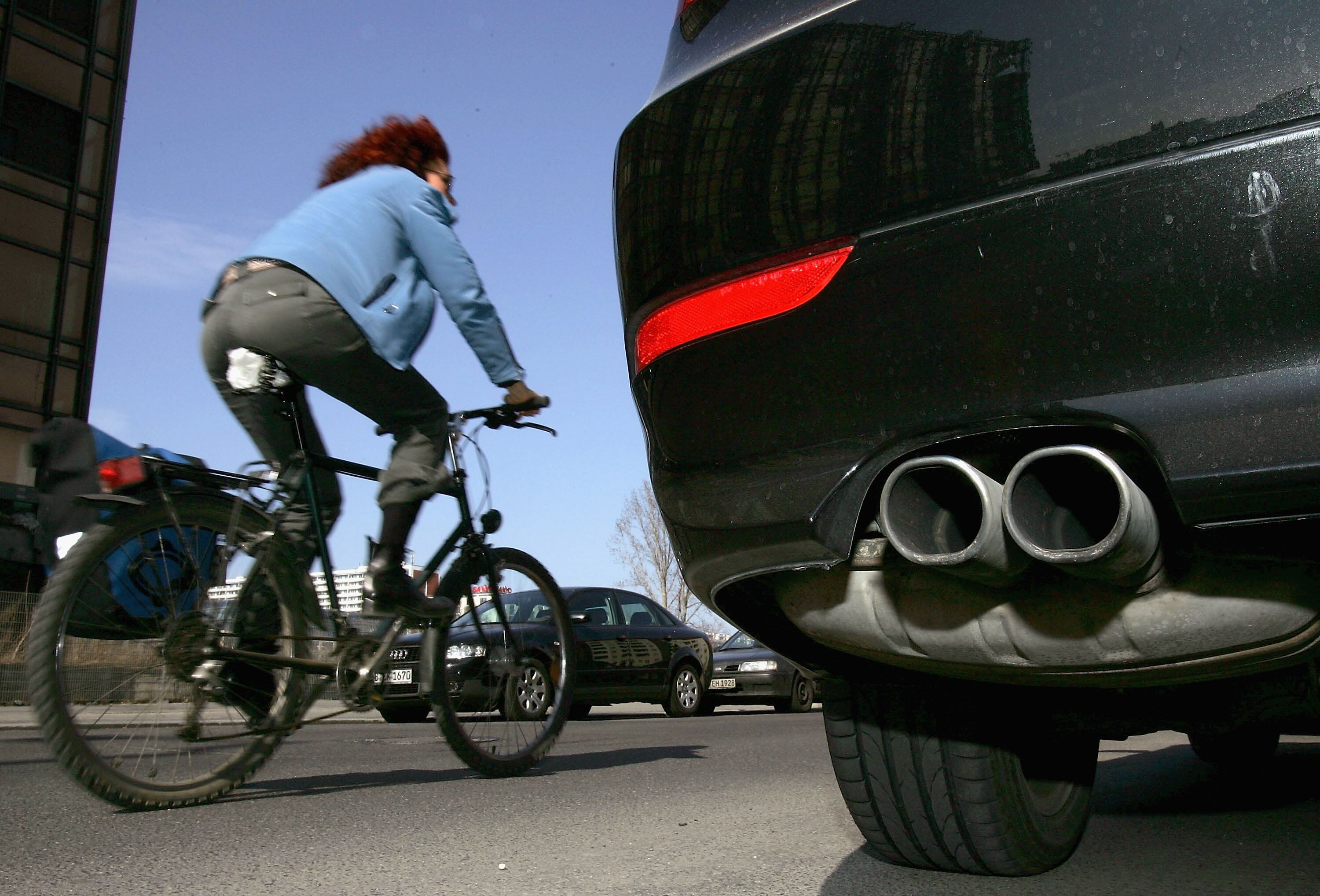 Una ciclista pasa junto a un coche aparcado en Berlín